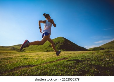 Young fitness woman trail runner running on high altitude grassland