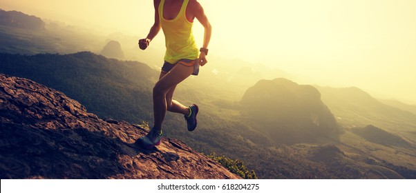 Young fitness woman trail runner running up at mountain top cliff edge - Powered by Shutterstock