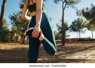 Young fitness woman wearing yoga pant and sports bra runner stretching legs before run on city park outdoor. Fitness and workout wellness, start straight concept of challenge or career path and change