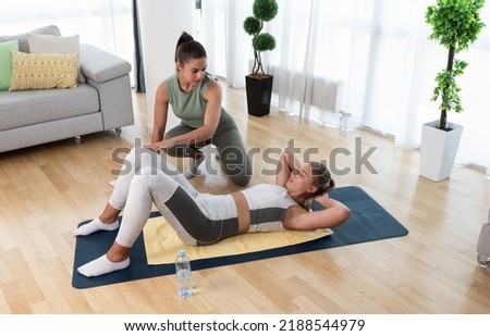 Young fitness and yoga instructor working in your home. Sporty educated woman helping young girl at her apartment at in home workout and training for healthy life. 