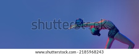 Young flexible girl, rhythmic gymnast athlete training with blue ball isolated on blue purple background in neon light. Concept of action, motion, sport life, motivation, competition. Copyspace for ad