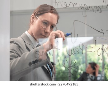 A young flight instructor stands concentrating writing and drawing on glass board. Teamwork preflight safety training or meeting and brainstorming with pilot in aviation business concepts. - Powered by Shutterstock