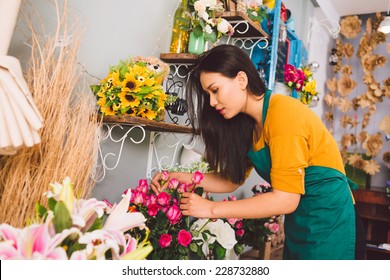 Young florist examining flowers at the shop