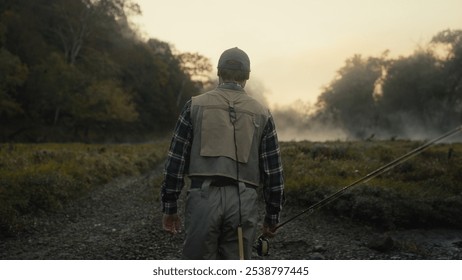 Young fly fisherman walking to a river at dawn - Powered by Shutterstock