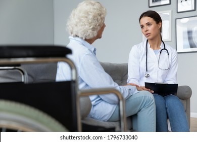 Young focused nurse visiting mature middle aged disabled patient for rehabilitation therapy at home. Skilled attentive millennial physiotherapist consulting senior old woman, healthcare concept. - Shutterstock ID 1796733040