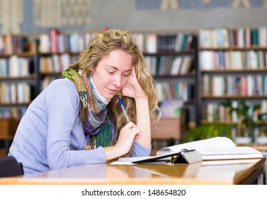 Young focused student using a tablet computer in a library 