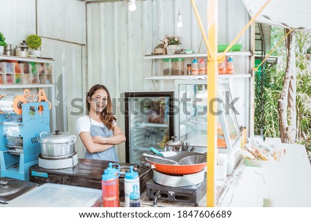 young food stall owner smiling to camera while standing on her truck container shop
