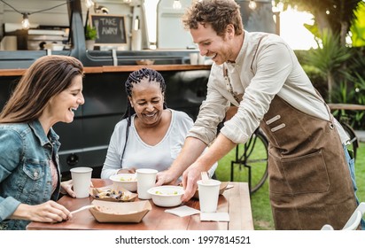 Young Food truck owner serving meal to customers table - Happy multiracial females having fun lunching together - Powered by Shutterstock