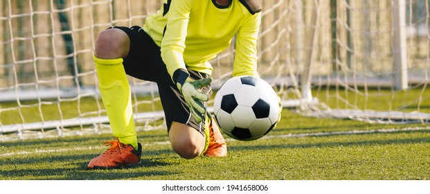 Young Football Galkeeper Catching Soccer Ball. Soccer Goalie in Action Saving Ball in a Goal - Powered by Shutterstock