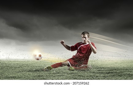 Young Football Player On Stadium Doing Slide Tackle