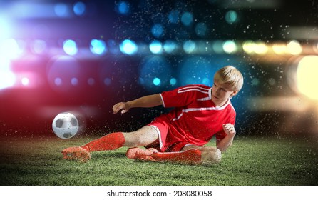 Young Football Player On Stadium Doing Slide Tackle