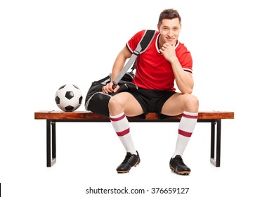 Young Football Player Sitting On A Wooden Bench And Looking At The Camera Isolated On White Background