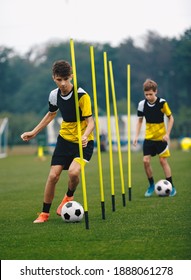 Young Football Players Running Slalom And Dribbling With Balls Between Training Poles. Soccer Practice For Teenage Boys. Junior Level Soccer Team Traing Unit