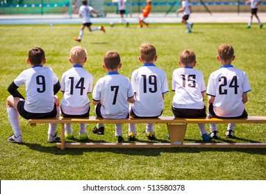 Young Football Players. Young Soccer Team Sitting On Wooden Bench. 