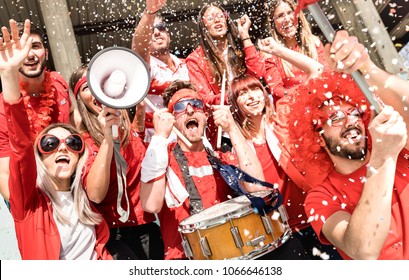 Young football supporter fans cheering with flag and confetti watching soccer match at stadium - Friends people group with red t-shirts having excited fun on sport world championship concept - Shutterstock ID 1066646138