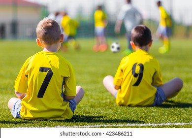 Young Football Team Wearing Sports Yellow Soccer Dress. Soccer Players On Sports Field. Football Soccer Match For Children. Youth Sports Team Sitting Together And Watching Football Soccer Game.