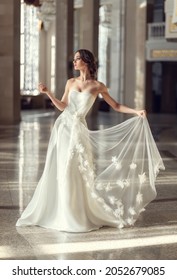 young fragile brunette girl. bride in a luxurious wedding dress in a chic interior with beautiful sunlight from the windows wedding hairstyle and makeup. photo for wedding salt, beauty salon