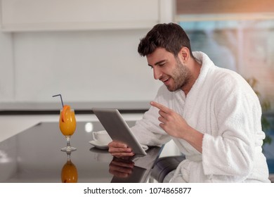 Young Freelancer In Bathrobe Working From Home Using Tablet Computer