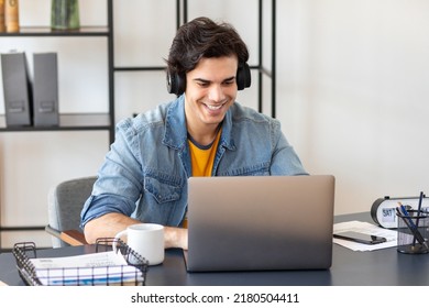 Young Freelancer Sitting Sitting At The Table At Home. Studying, Distance Learning, Online Education Concept. Happy Male Student Or Entrepreneur Using Laptop Computer Working In Modern Office