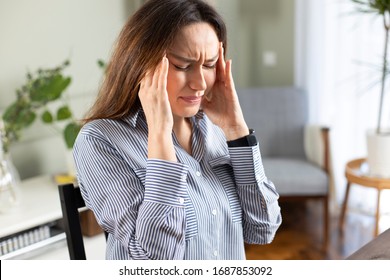 Young freelancer woman suffering with a headache at home office