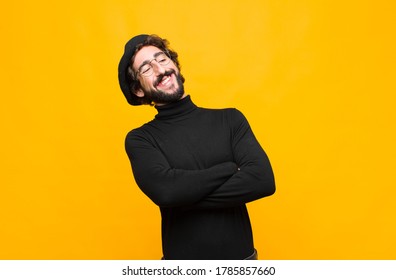 Young French Artist Man Laughing Happily With Arms Crossed, With A Relaxed, Positive And Satisfied Pose Against Orange Wall