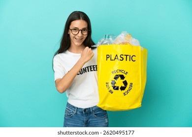 Joven francesa sosteniendo una bolsa llena de botellas de plástico para reciclar celebrando una victoria