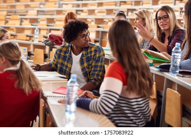 Young freshman students branstorming and comparing notes in amphitheater - Shutterstock ID 1757083922