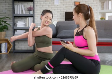 Young Friend Women Practicing Yoga At Home Unsing Smart Phone Via Online Class With Professional Instructor, Sport And Healthy Lifestyle Concept.