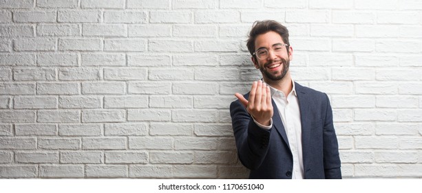 Young friendly business man inviting to come, confident and smiling making a gesture with hand, being positive and friendly