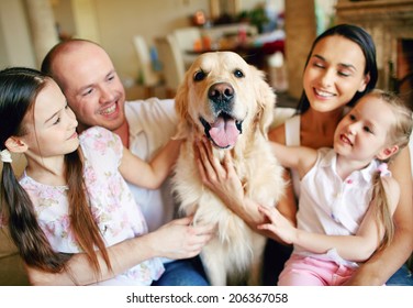 A Young Friendly Family Of Four Cuddling Their Pet