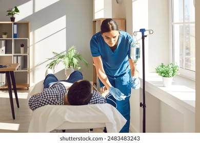 Young friendly nurse help sick man in receiving IV drip infusion and vitamin therapy in medical clinic. Female doctor giving consultation to her male patient lying on the couch in hospital. - Powered by Shutterstock