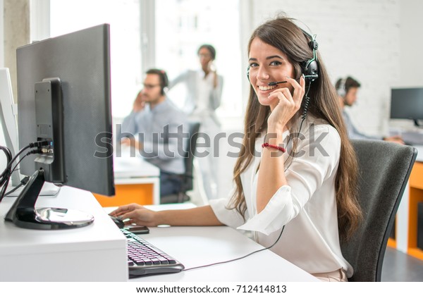 Young friendly operator woman agent with headsets\
working in a call centre.