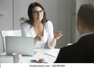 Young friendly smiling businesswoman wearing glasses talking to a male candidate at the desk, interviewing a job applicant. Rear view at a man. Business concept photo