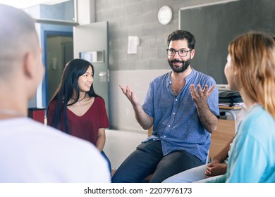 Young friendly teacher listening and talking with teenager students - Group discussion in High School - Shutterstock ID 2207976173