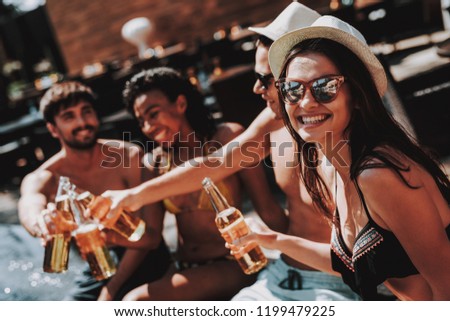Young Friends with Alcoholic Drinks at Poolside. Group of Young Smiling People holding Bottles of Beer and having Fun at Poolside. Happy Friends Enoying Pool Party. Summer Vacation Concept