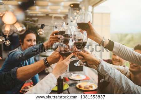 Young friends celebrating at dinner at sunset - Detail of hands while toasting with glasses of wine - Happy people at a terrace party after the harvest before sunset - Concept of friendship
