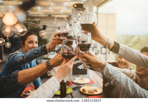Young friends celebrating at dinner at sunset
- Detail of hands while toasting with glasses of wine - Happy
people at a terrace party after the harvest before sunset - Concept
of friendship