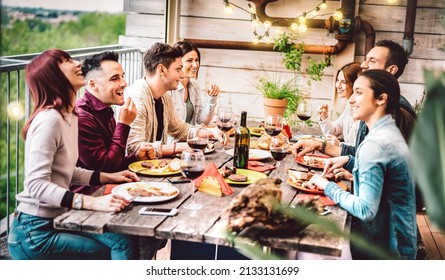 Young friends dining and having fun drinking wine together on patio roof top supper party event - Happy people eating bbq food at barbeque terrace - Millenial life style concept on warm evening filter - Shutterstock ID 2133131699