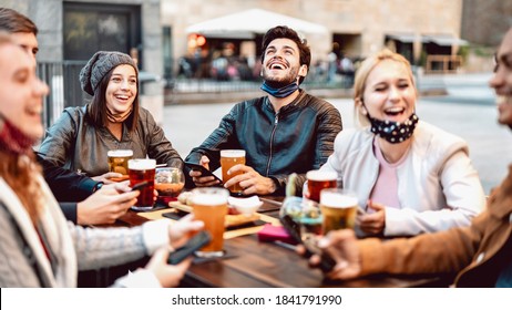 Young friends drinking beer wearing face mask - New normal lifestyle concept with people having fun together talking on happy hour at hipster brewery bar - Bright warm filter with focus on central guy - Powered by Shutterstock