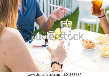 Woman holding lemonade glass and friends cooking in barbecue