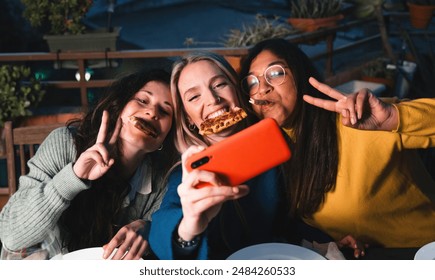 Young friends eating pizza in outdoor restaurant. Group of women having fun taking self photo together - Powered by Shutterstock