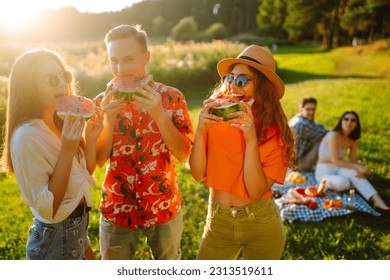 Young friends  eating watermelon on the picnic.  People enjoy summer time. People, lifestyle, travel, nature and vacations concept. - Powered by Shutterstock