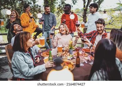 Young friends having fun drinking beer and wine on balcony at farmhouse dinner pic nic party - Hipster millennial people eating bbq food at fancy restaurant together - Dinning life style concept