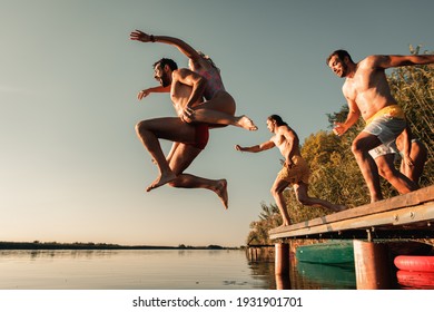 Young friends having fun enjoying a summer day swimming and jumping at the lake. - Powered by Shutterstock