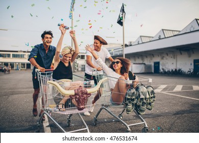 Young friends having fun on shopping trolleys. Multiethnic young people racing on shopping cart. - Shutterstock ID 476531674