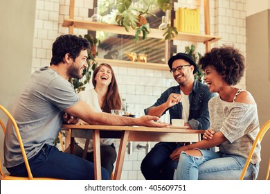 Young friends having a great time in restaurant. Group of young people sitting in a coffee shop and smiling.