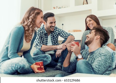 Young Friends Having A Great Time In Living Room.Group Of Young People Sitting And Smiling With Coffee.