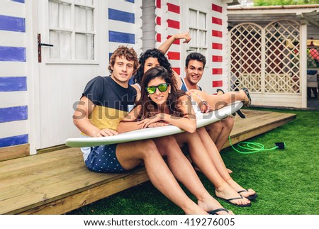 Young friends holding woman on top of surfboard