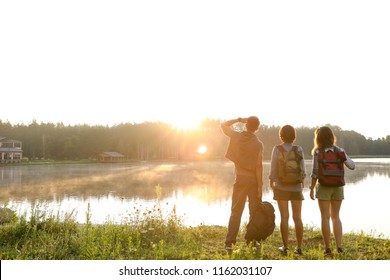 Young Friends On Shore Of Beautiful Lake. Camping Season