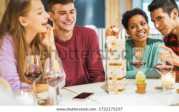 Young friends\
playing board games at home - Happy people having fun doing party\
in living room house at evening time - Fest during isolation\
quarantine - Focus on african girl\
face
